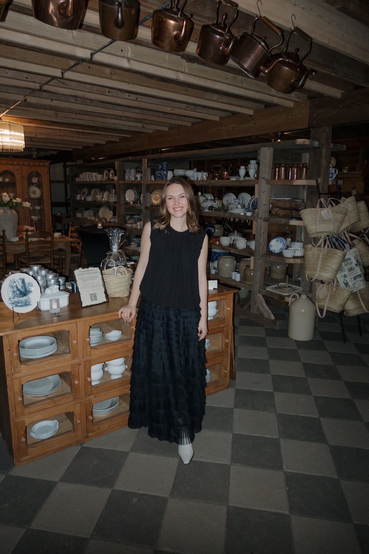 A woman stands among antique pine cabinets, blue and white transferware and copper pots inside the Marvella Mercantile barn