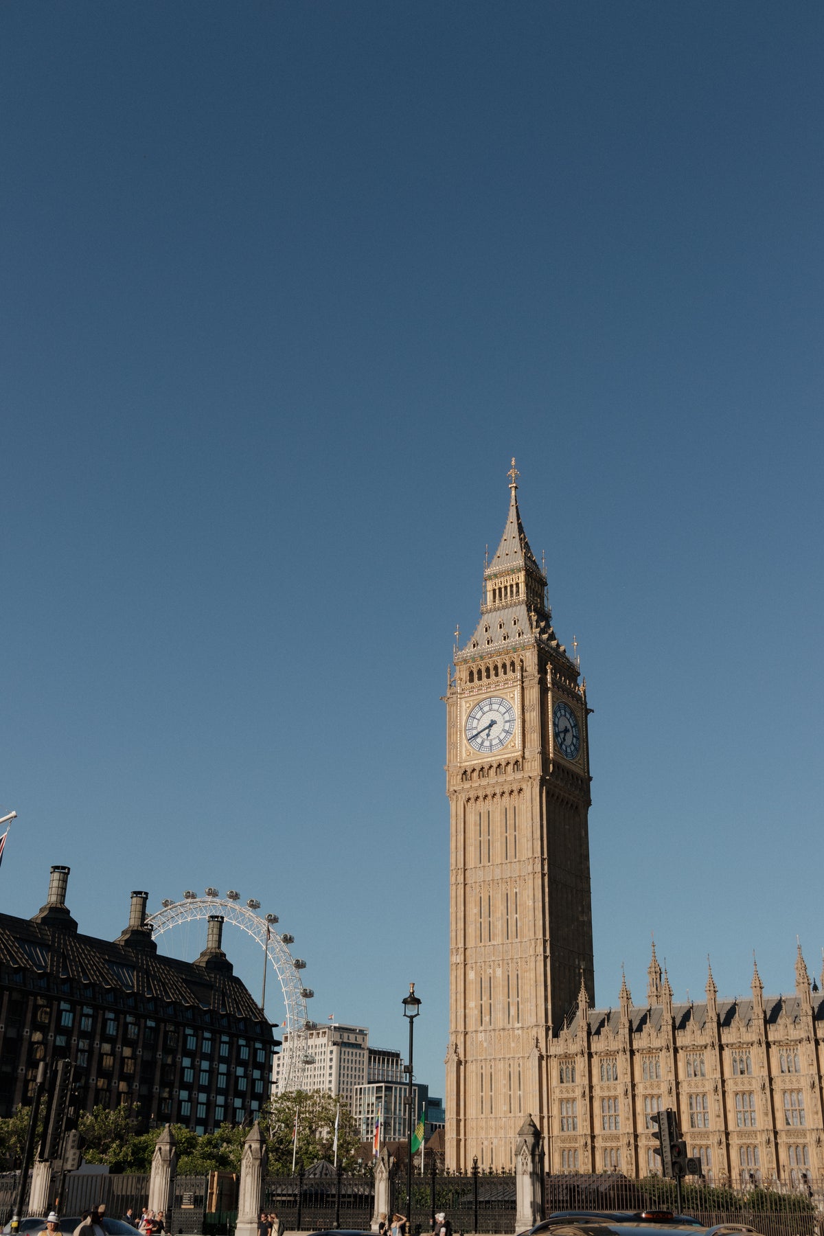 A stone cottage behind a low stone wall covered in climbing roses