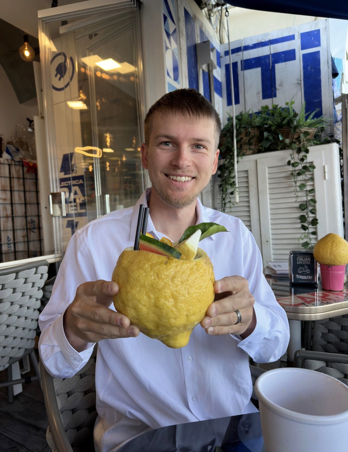 A man holds a drink served in an oversized lemon at a café in Capri, Italy