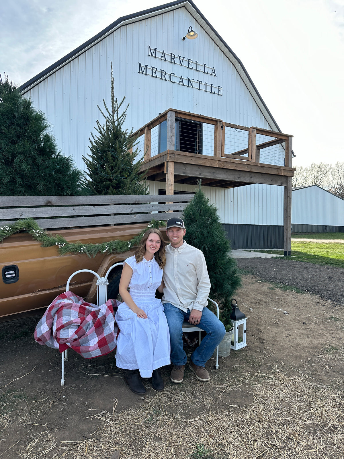 A couple sits on a bench outside the white Marvella Mercantile barn in Yutan, Nebraska, just outside Omaha