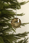 Round amber faceted glass Christmas ornament on a silver cord hanging on an evergreen tree