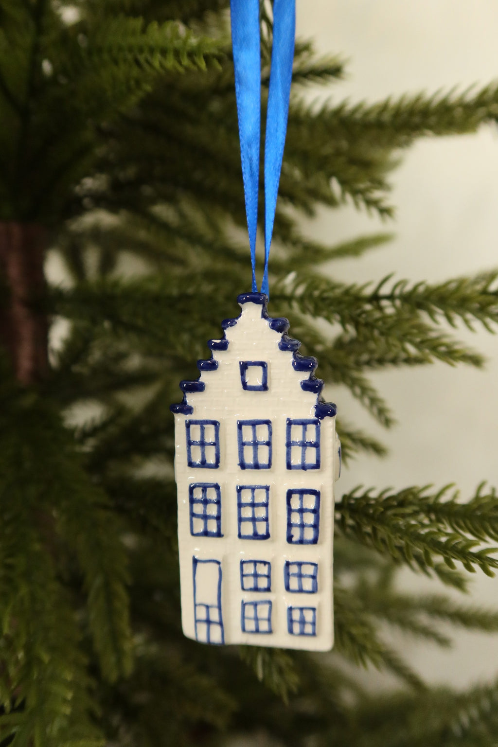 Front view of the Delft blue canal house ornament showing its hand-painted windows, door and stepped gable