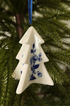 Closer view of the Delft blue tree ornament showing its glossy white glaze and blue rose and leaf painting