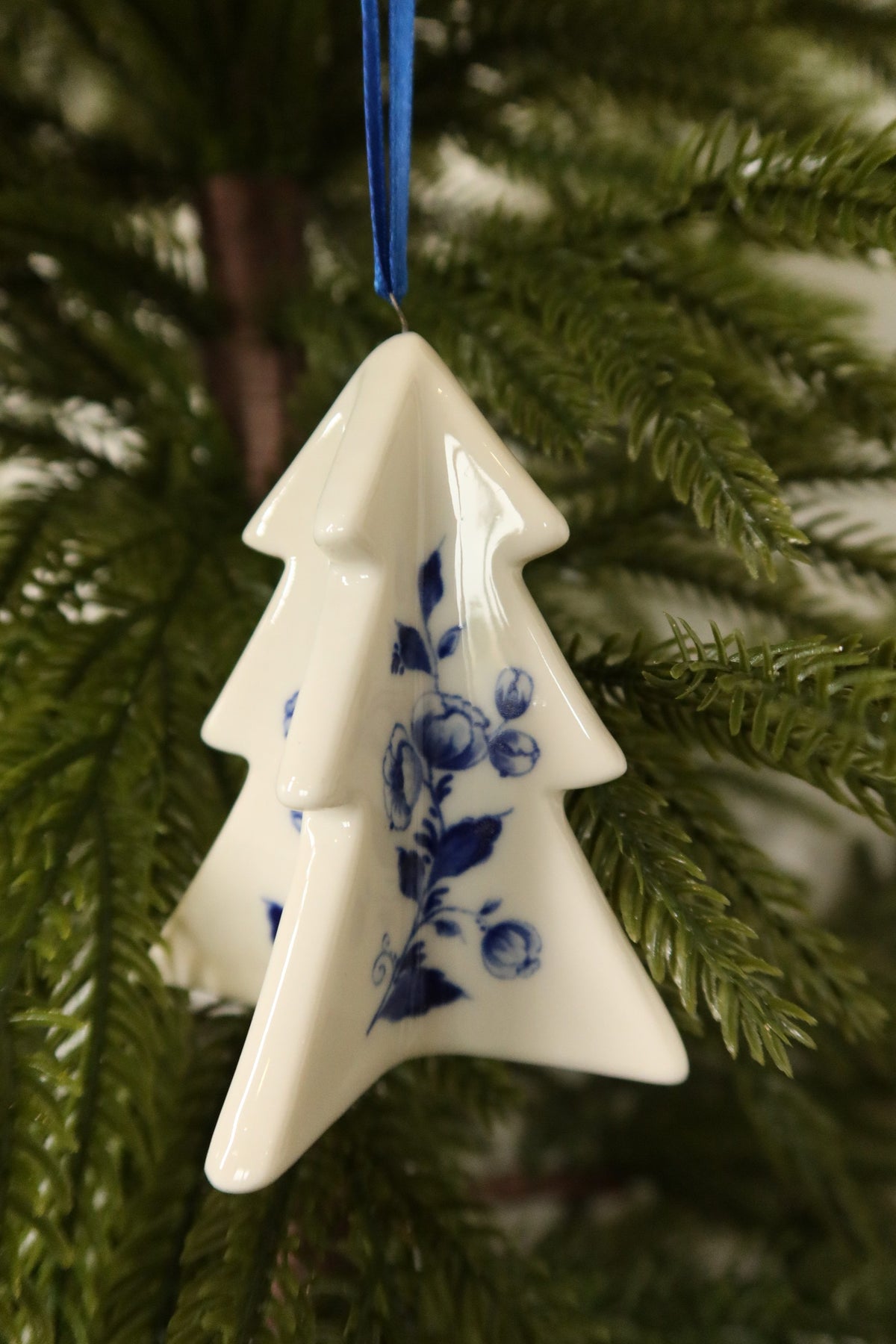Closer view of the Delft blue tree ornament showing its glossy white glaze and blue rose and leaf painting