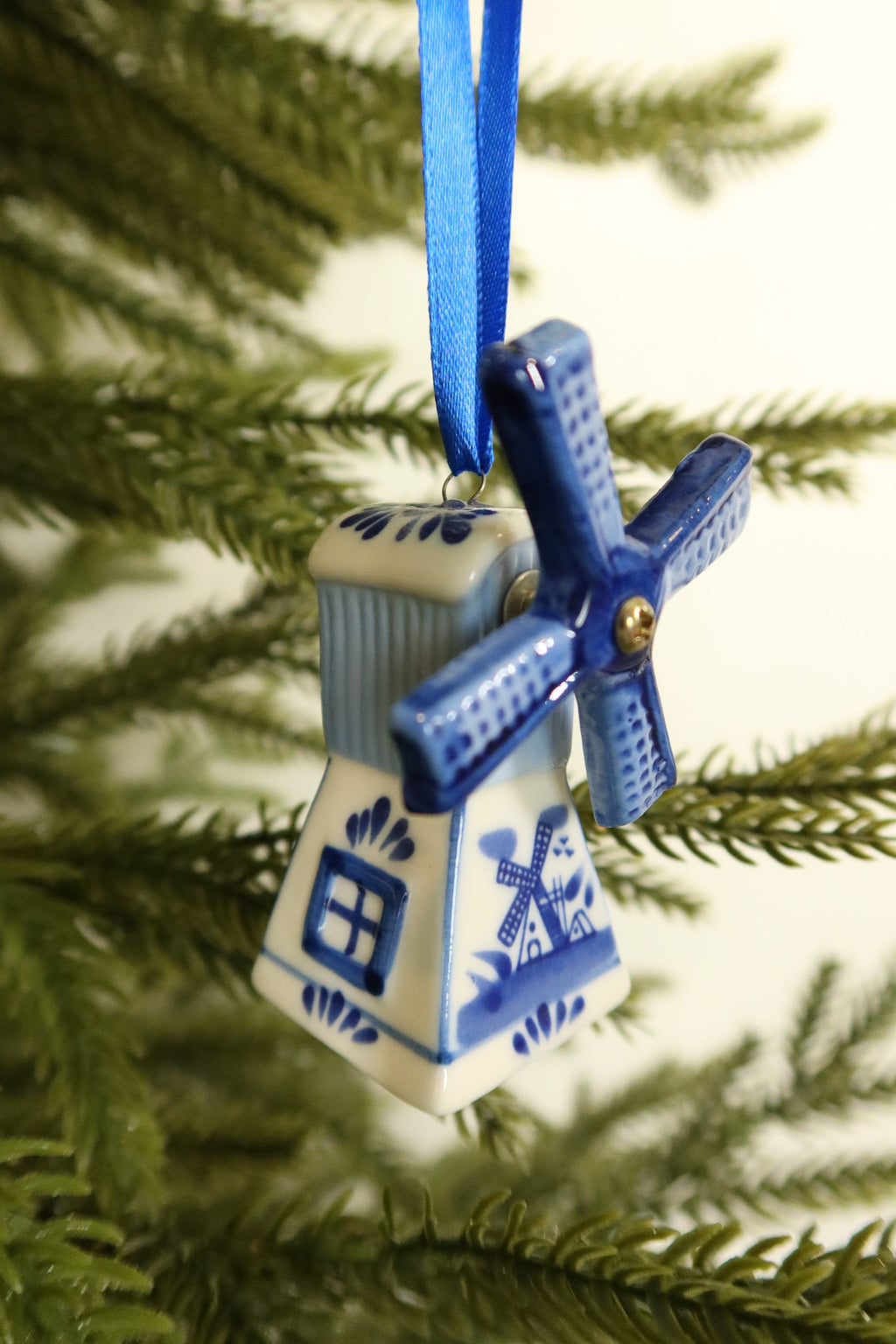 Side view of the Delft blue windmill ornament showing its painted window, ribbed roof and floral details