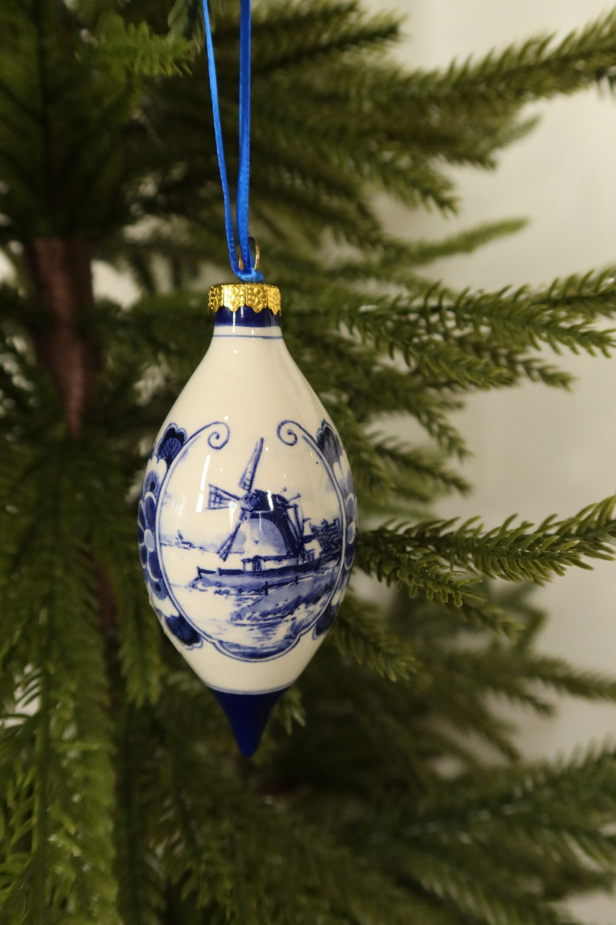 Close-up of the hand-painted Delft blue windmill landscape and scrolled floral border on the teardrop ornament