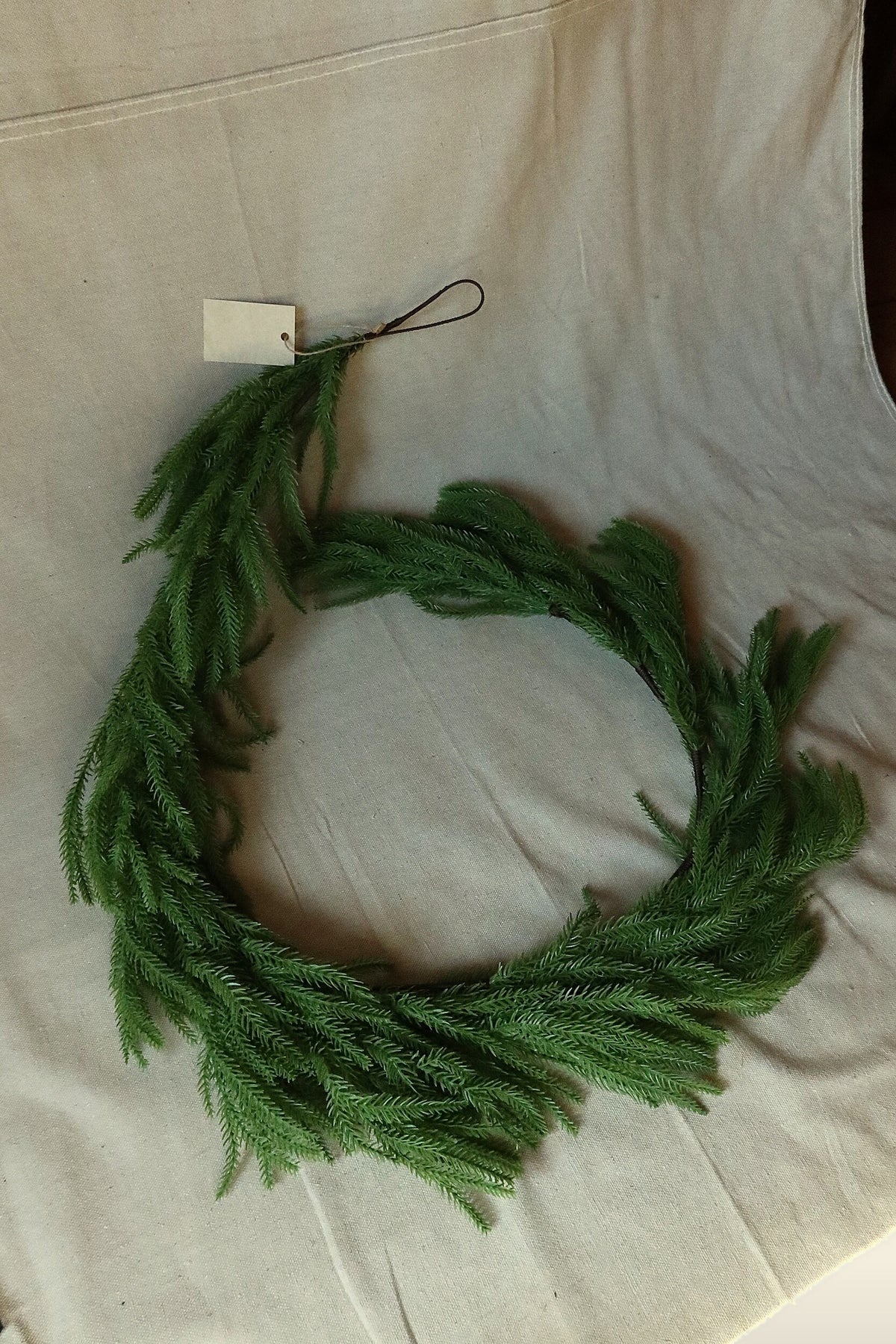 Full length of the 59 inch faux Norfolk pine garland laid out in a loose curve