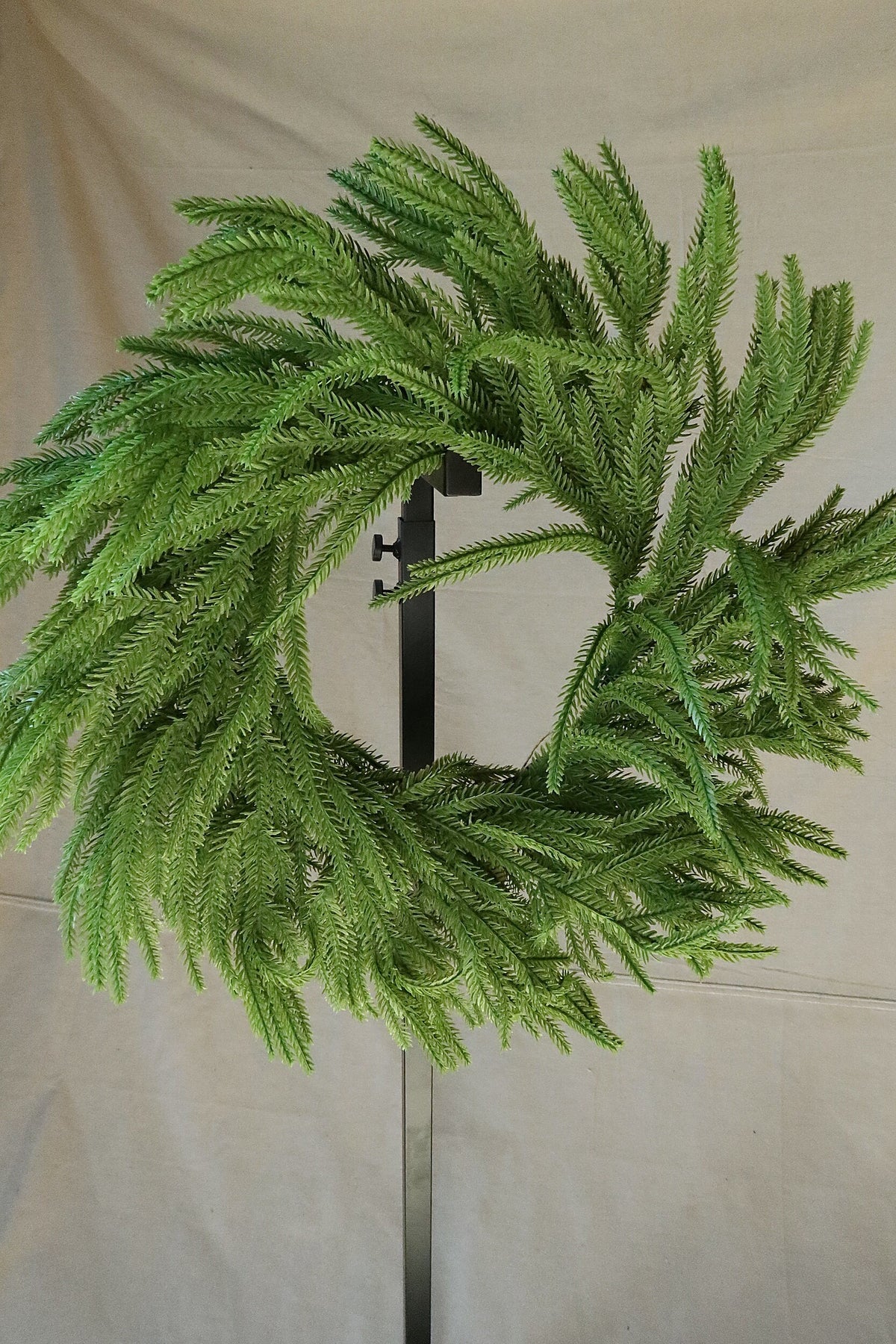 Closer front view of the 24 inch faux Norfolk pine wreath showing its full, layered branches