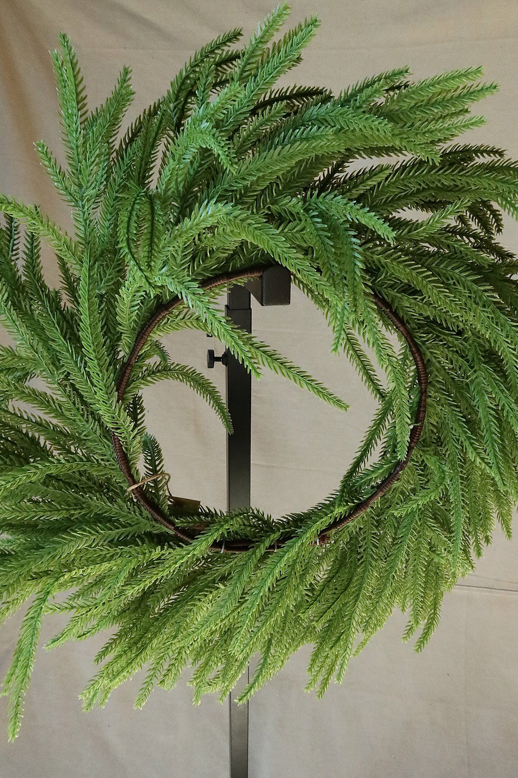 Back of the 24 inch faux Norfolk pine wreath showing the brown wrapped ring frame