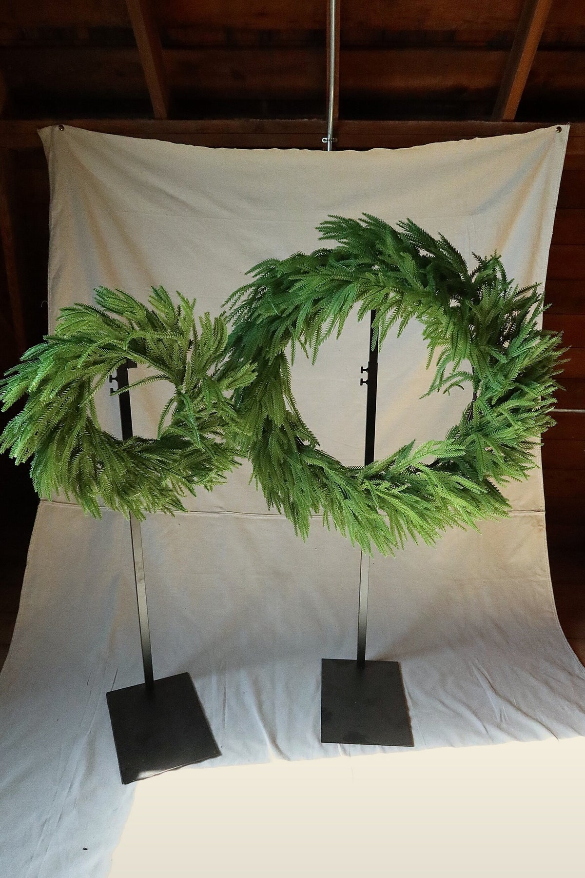 24 inch faux Norfolk pine wreath on the left beside the 36 inch wreath for size comparison