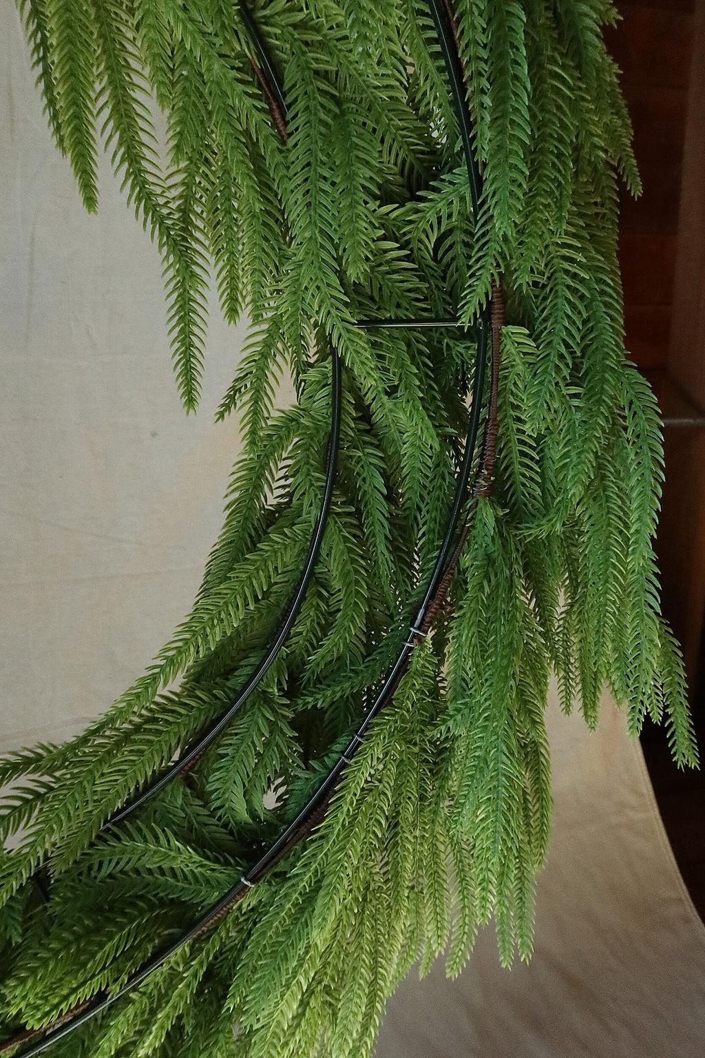 Close-up of the double-ring frame and hanging branches on the back of the 36 inch faux Norfolk pine wreath