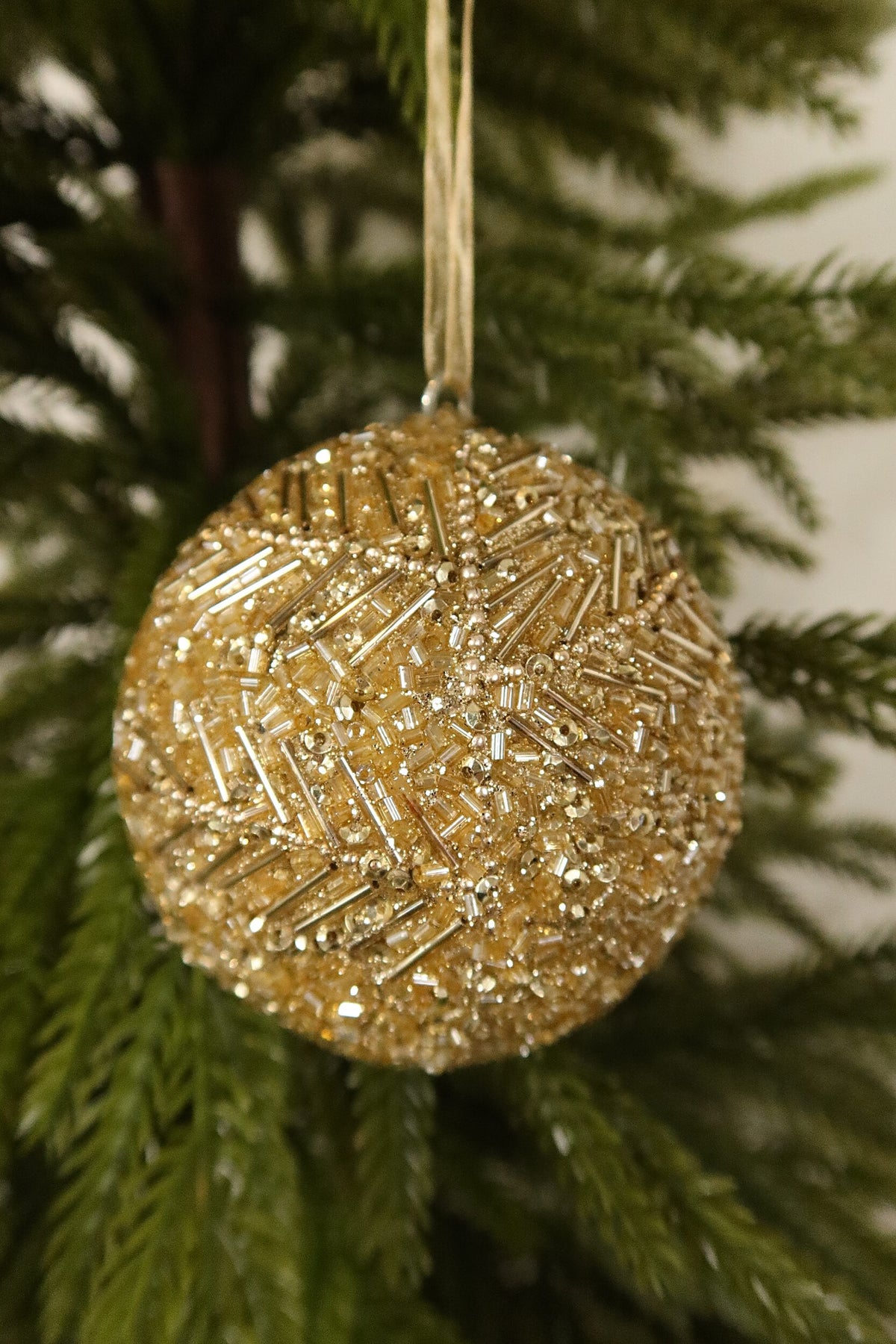 Closer view of the gold beaded ball ornament showing its bugle beads, sequins and pearl bead branches