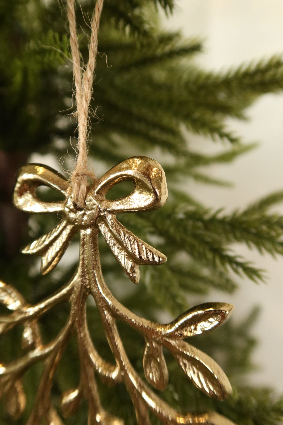 Close-up of the gold bow and jute twine hanger at the top of the metal mistletoe ornament