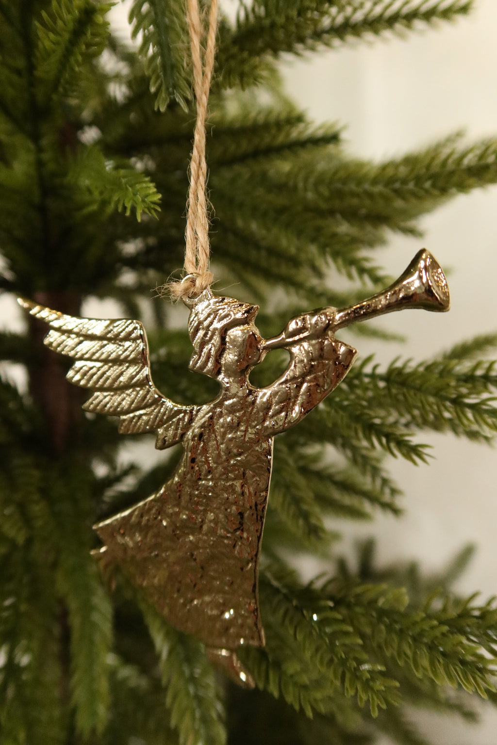 Closer view of the gold angel ornament showing its trumpet, feathered wings and hammered texture