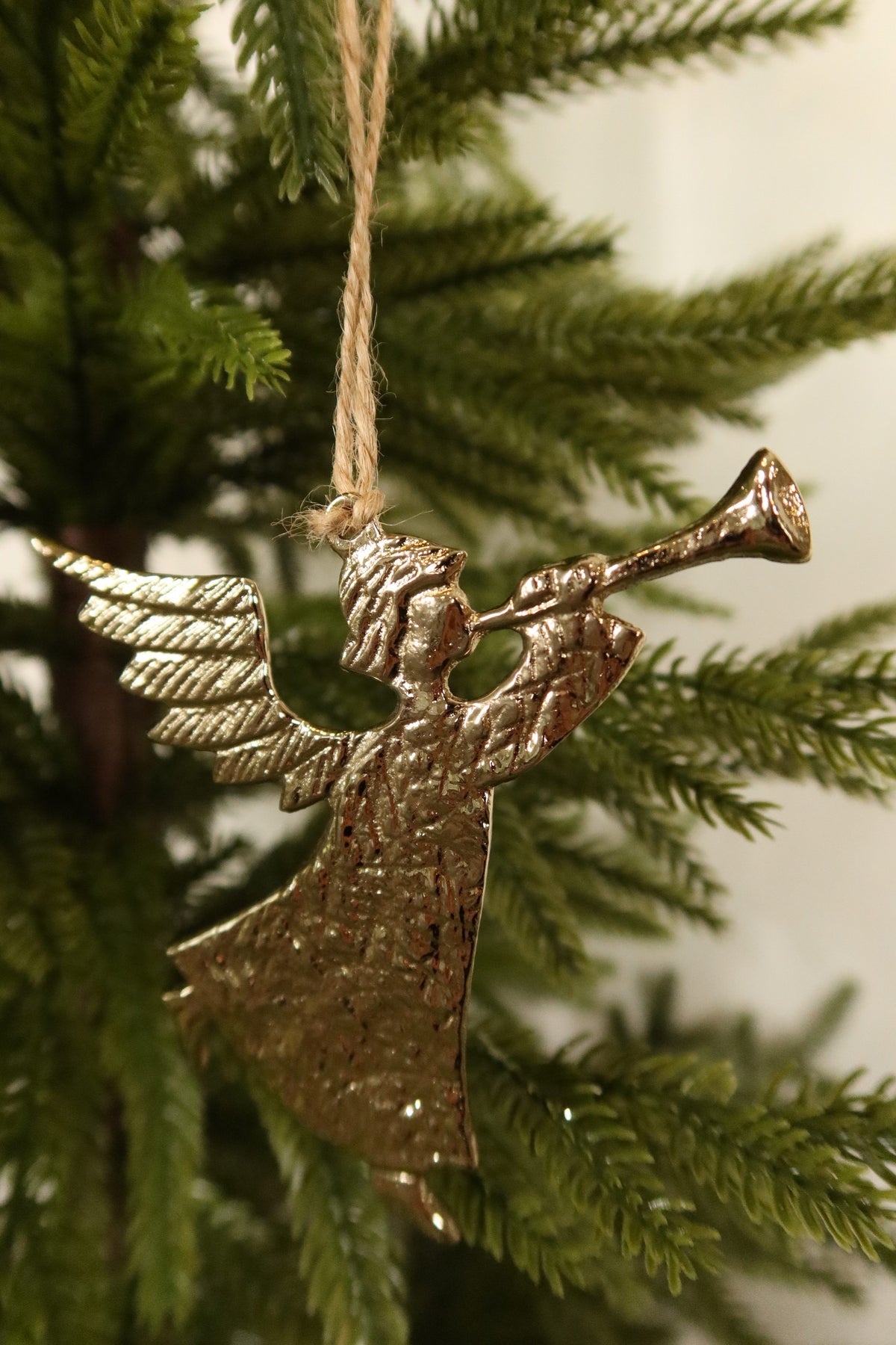 Closer view of the gold angel ornament showing its trumpet, feathered wings and hammered texture