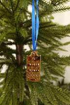 Gold mini canal house ornament with a bell gable hanging from a blue ribbon on an evergreen tree