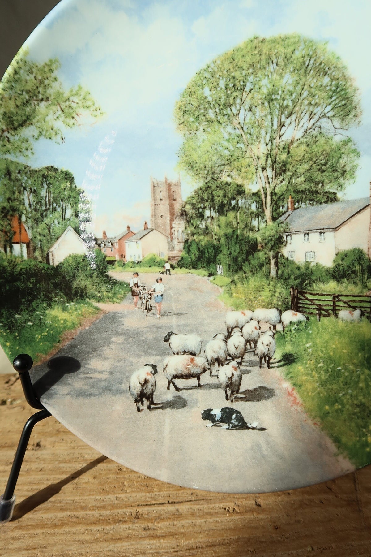 Close detail of the flock of sheep, sheepdog, summer trees and church tower on the Royal Doulton The Summer Field plate by Clive Madgwick