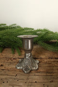 Silver cast iron taper candle holder, 2.5 in, with a leaf-patterned floral base, on a rustic wood table with greenery