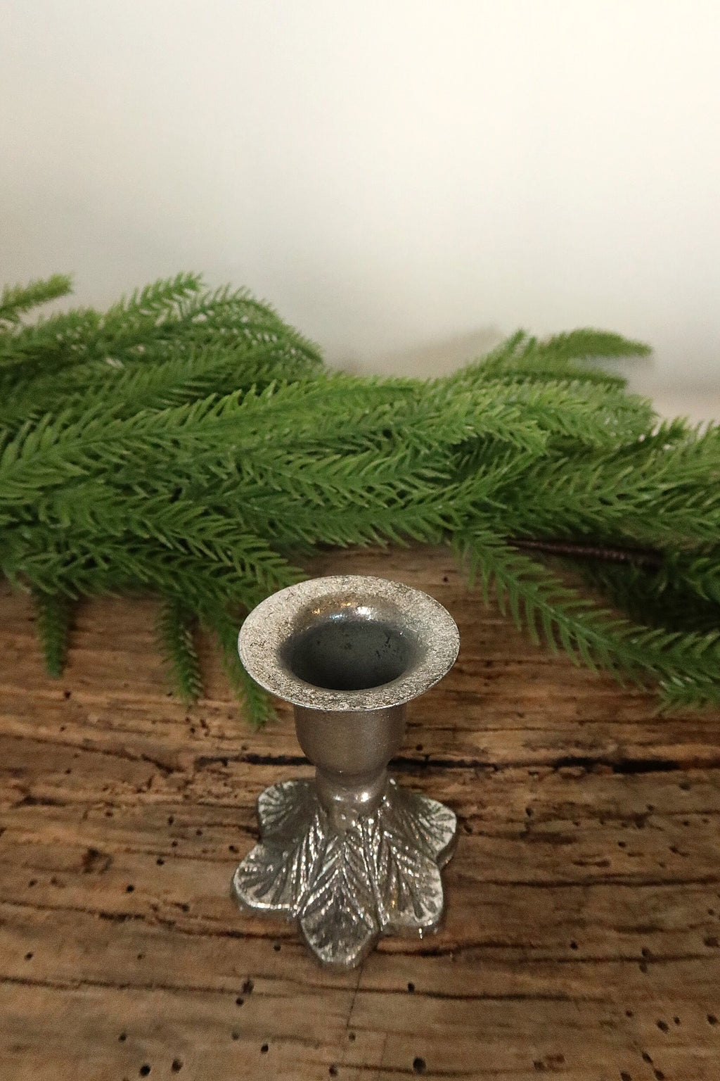 Top view of the 2.5 in silver cast iron taper candle holder showing the candle cup and leaf-patterned base