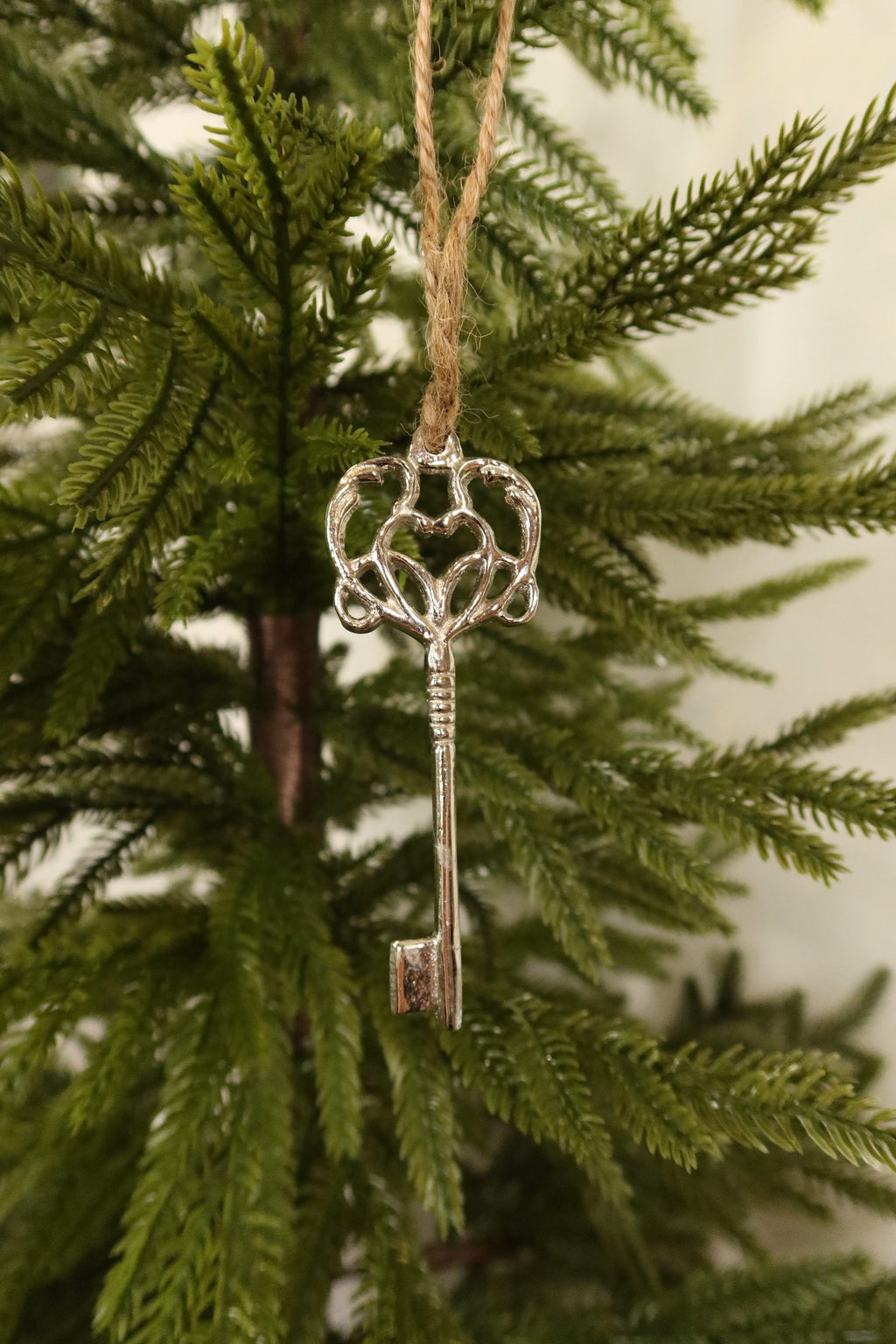 Silver skeleton key ornament on jute twine among green pine branches