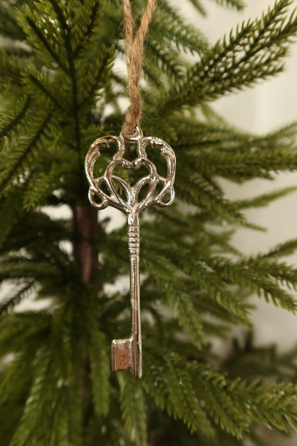 Closer view of the full silver metal key ornament hanging on a Christmas tree