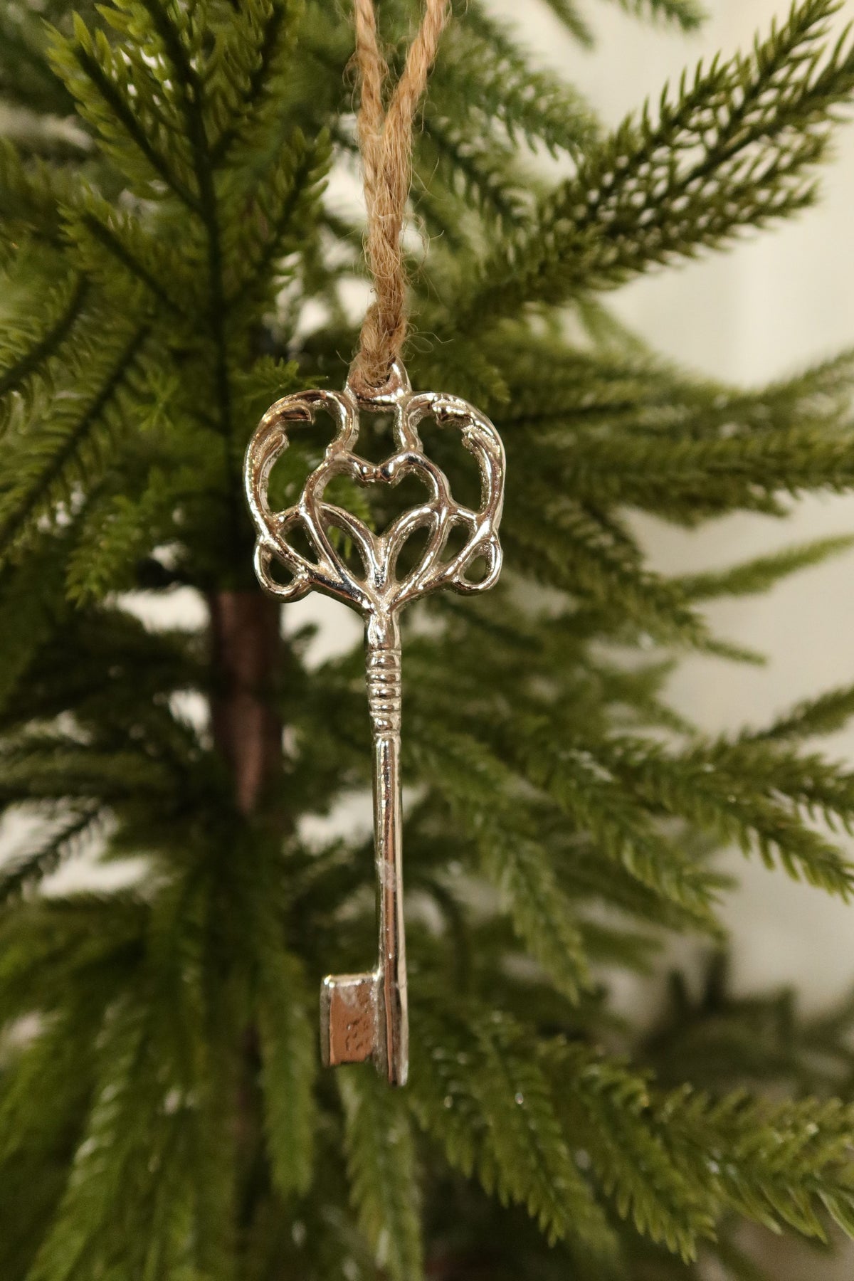 Closer view of the full silver metal key ornament hanging on a Christmas tree