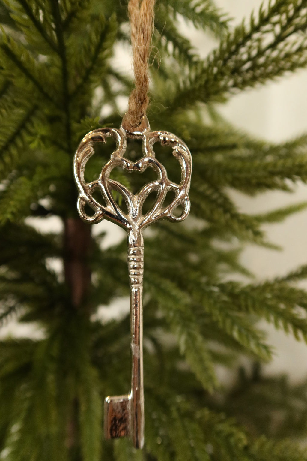 Close-up of the polished silver key ornament showing its scrolled heart bow and ridged shaft