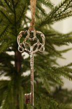 Close-up of the polished silver key ornament showing its scrolled heart bow and ridged shaft