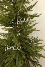Silver rhinestone Joy, Love and Peace ornaments hanging together on a Christmas tree