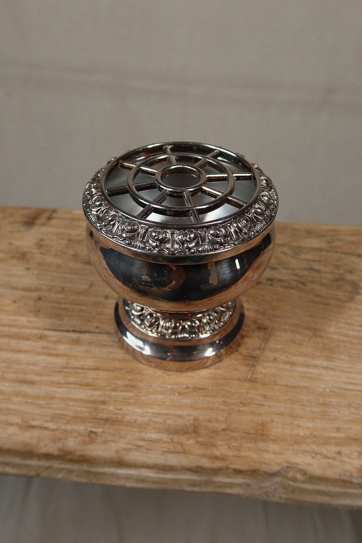 View from above of the spoke-pattern grille on the Ianthe silver plate rose bowl, on a rustic wooden bench